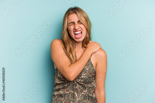 Young caucasian blonde woman isolated on blue background  having a shoulder pain.