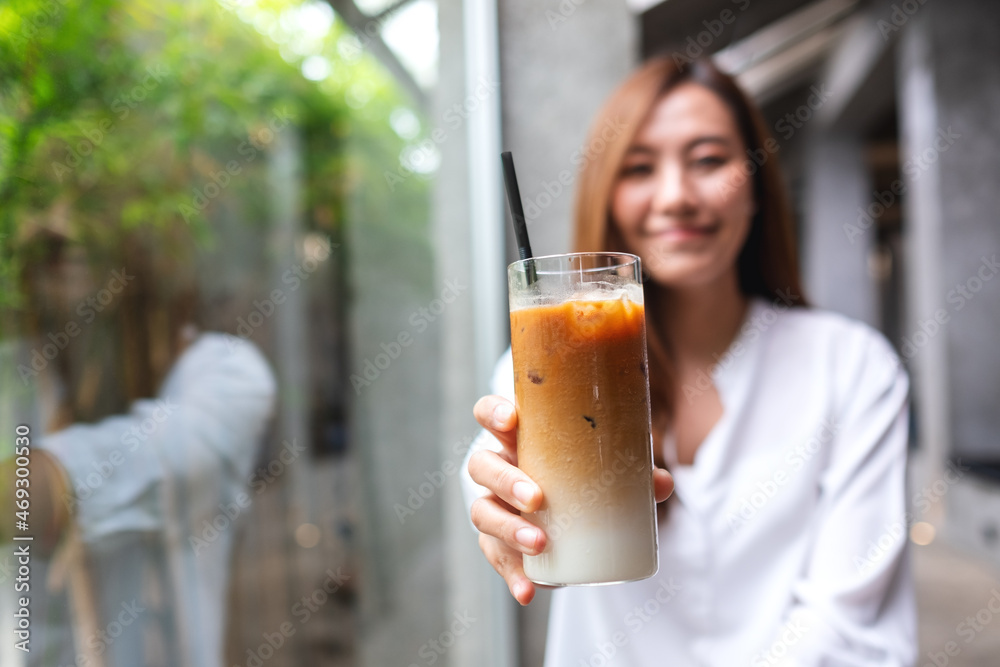 A young asian woman holding and pointing finger at a glass of iced coffee