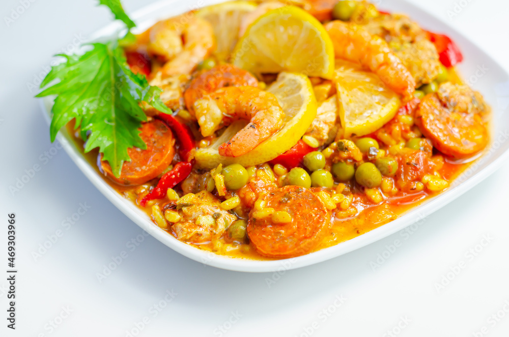 Delicious paella, cooked risotto rice with chicken thigh, king prawns, tomatoes and chorizo Delicious paella, cooked risotto rice with chicken thigh, king prawns, tomatoes and chorizo