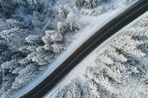 Aerial view of winter landscape with snow covered mountain woods and winding forest slippery road © bilanol