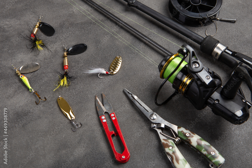 Fishing tackle - fishing spinning rod, hooks and lures on gray background. Active hobby recreation concept. Fishing tackle - fishing spinning rod, hooks and lures on gray background. Active hobby recreation concept.