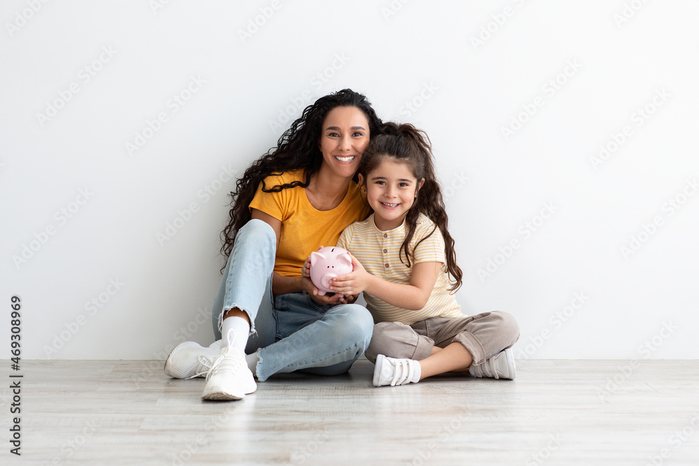 Family Savings. Happy Arab Mother And Cute Little Girl Posing With Piggibank Family Savings. Happy Arab Mother And Cute Little Girl Posing With Piggibank