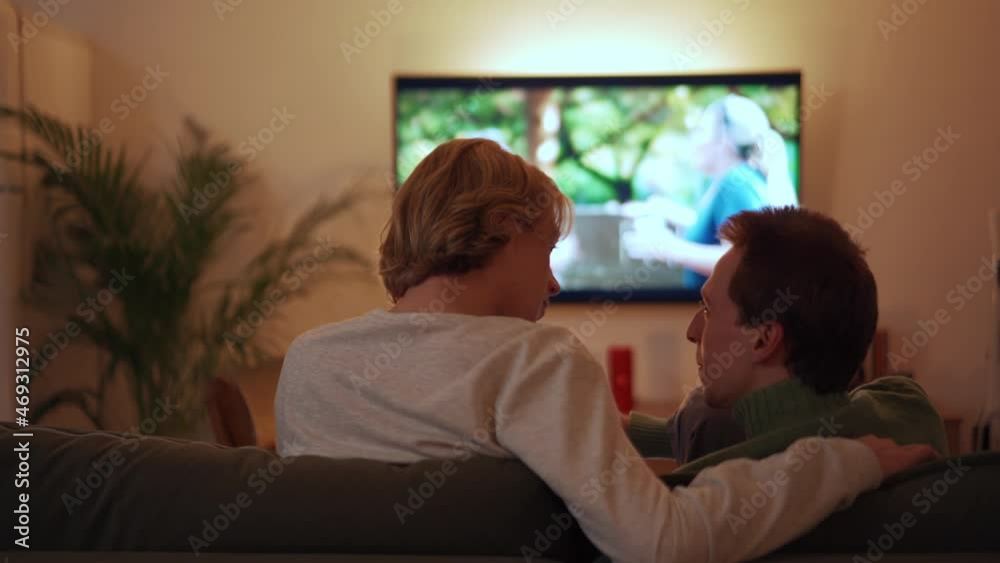 Back view of positive gay couple watching something on TV Back view of positive gay couple watching something on TV