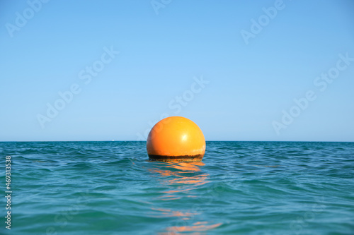 Yellow buoy floating on sea surface as marker for swimming restriction in deep water at tropical resort. Human life safety concept © bilanol