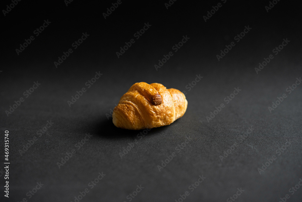 Croissant pequeño en un fondo negro Croissant pequeño en un fondo negro