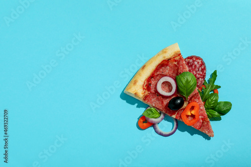 Slice of Salami pizza on blue background