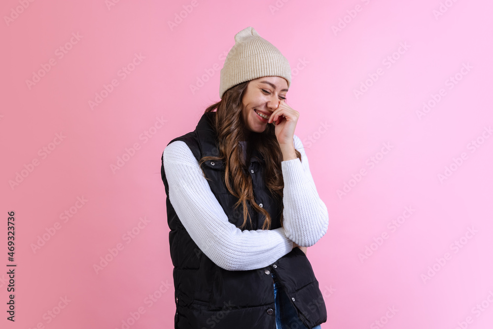 Happy, joyful young beautiful girl in knitted hat isolated on pink studio background in neon light. Concept of emotions, facial expression Happy, joyful young beautiful girl in knitted hat isolated on pink studio background in neon light. Concept of emotions, facial expression