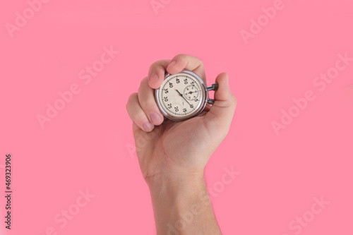 Fototapeta Naklejka Na Ścianę i Meble -  Man hand holding stopwatch on pink background.