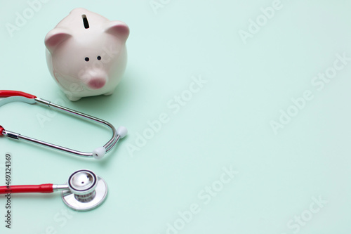 Pink piggy bank with stethoscope on green background