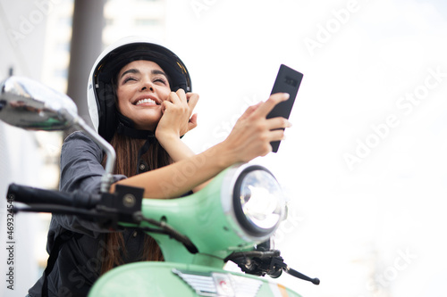 Beautiful woman getting ready for a ride on scooter. Beautiful happy lady taking selfie photo..