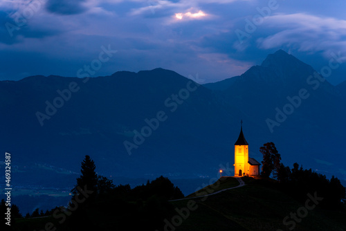 Illuminated Primoz Church in Jamnik Slovenia at Evening. Alpine Landscape