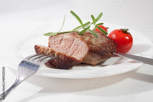 Appetizing steak well done on a white plate with tomatoes and rosemary
