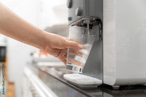 Close-up hand of Woman drinking water is poured from water cooler into the glass, drinking water machine photo