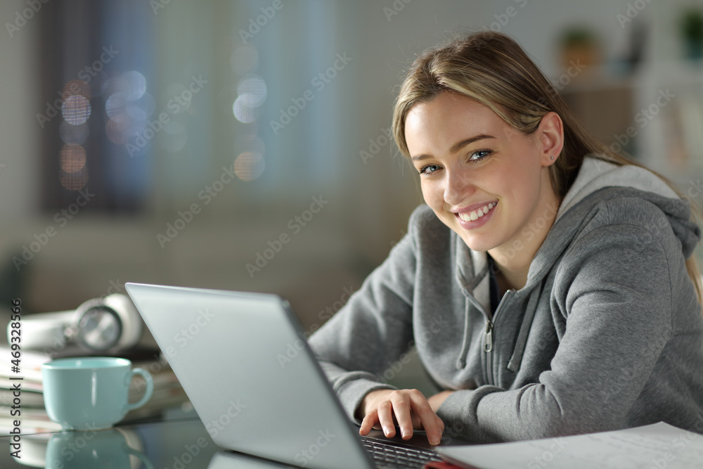 Happy student using laptop looking at you Happy student using laptop looking at you