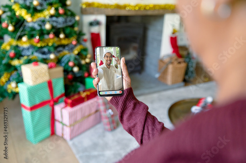 Woman making smartphone christmas video call with smiling biracial man