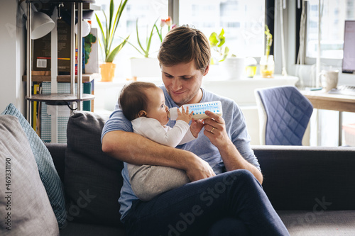 Man Feeding Infant Daughter From Milk Bottle