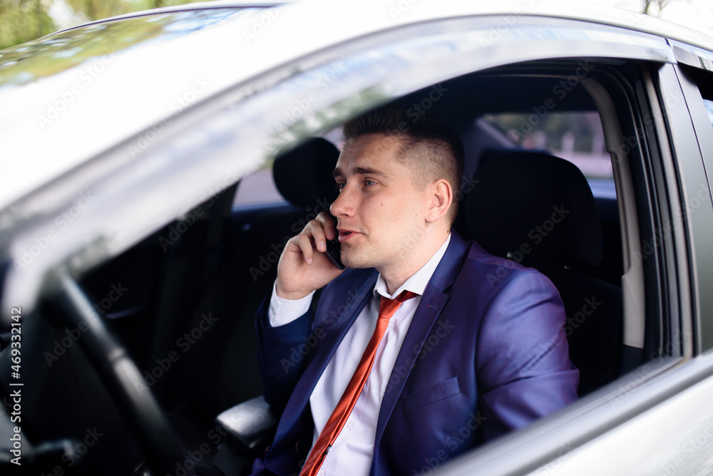 A male business man is talking on the phone in a car. A male business man is talking on the phone in a car.