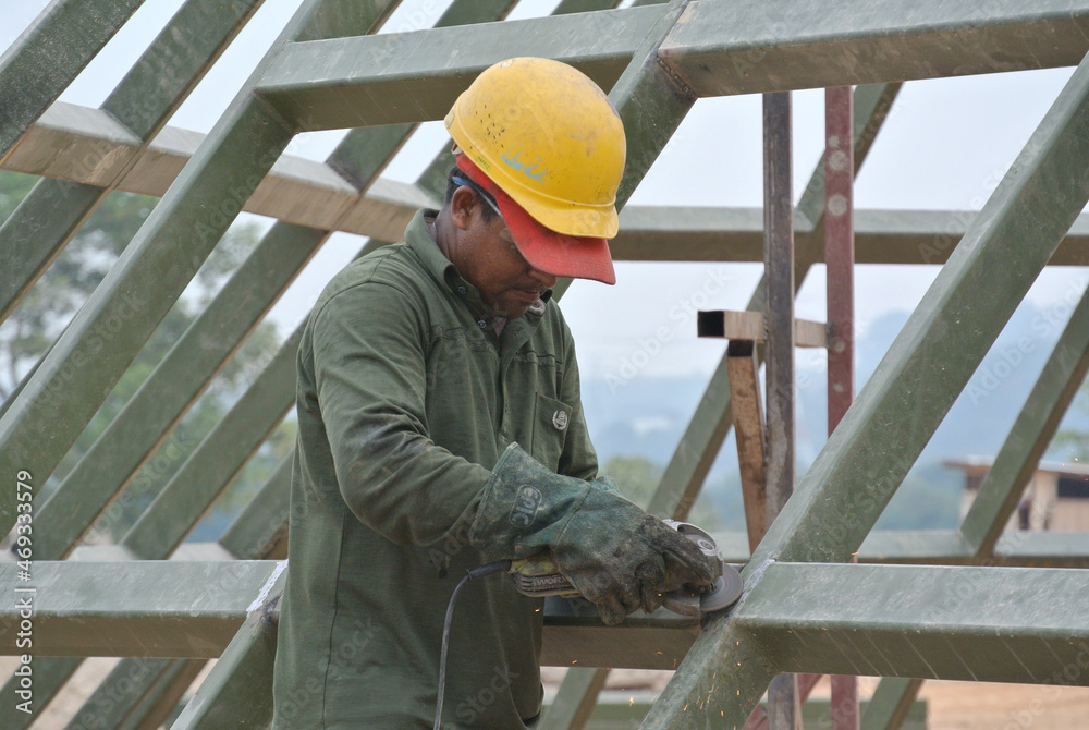 SELANGOR, MALAYSIA – MARCH 15, 2015: Construction workers cutting metal using mobile grinder at the construction site in Selangor, Malaysia. SELANGOR, MALAYSIA – MARCH 15, 2015: Construction workers cutting metal using mobile grinder at the construction site in Selangor, Malaysia.