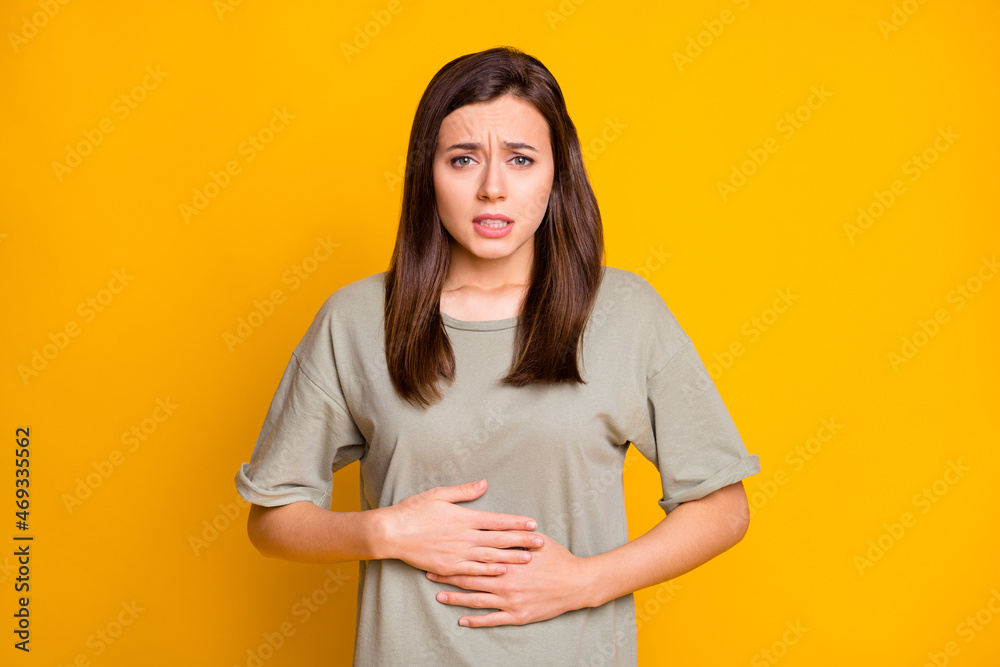 Portrait of pretty sick brown-haired girl touching abdomen feeling bad isolated over bright yellow color background - obrazy, fototapety, plakaty 