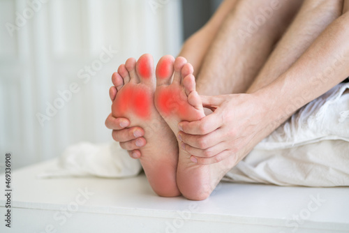 Foot pain, man suffering from feet ache in home interior