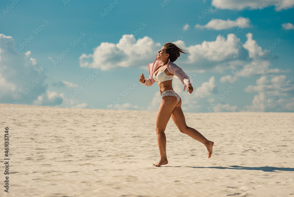 Naklejka premium Happy middle aged woman running on sandy beach