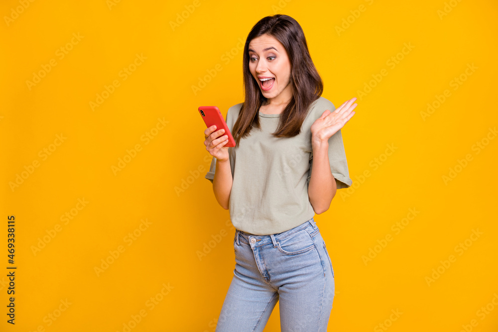 Photo of astonished happy young woman hold phone read notification sale isolated on vivid yellow color background Photo of astonished happy young woman hold phone read notification sale isolated on vivid yellow color background