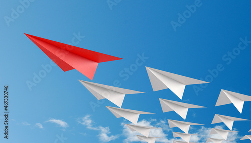 Red paper plane as leader of others on a blue background with clouds