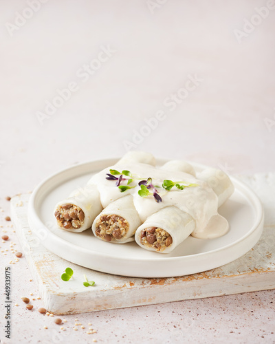Gluten free plant based cannelloni with quinoa and lentils, vegan bechamel , light background. Macrobiotic diet. Meat alternative Vegetarian food concept. photo