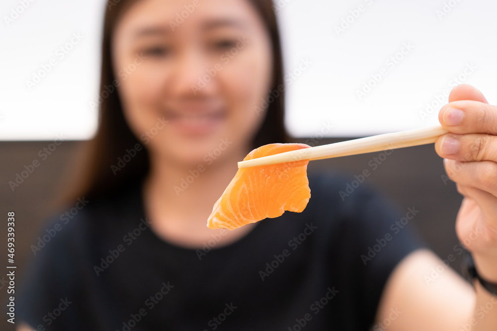 Beautiful Asian young woman enjoy eating a salmon sashimi. Beautiful Asian young woman enjoy eating a salmon sashimi.