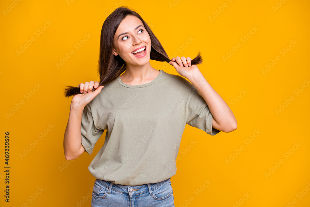 Portrait of pretty cheerful dreamy brown-haired girl having fun making tails looking aside isolated over bright yellow color background Portrait of pretty cheerful dreamy brown-haired girl having fun making tails looking aside isolated over bright yellow color background