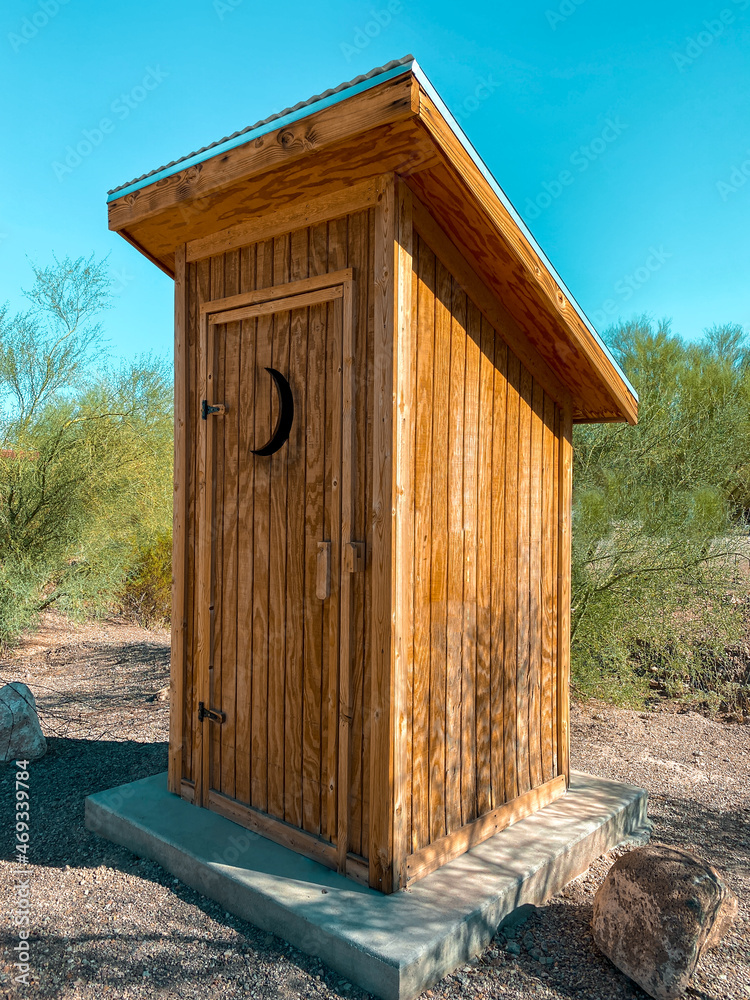 Old fashion country outhouse with slanted tin roof and moon shaped