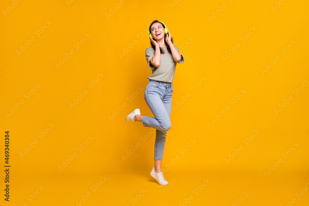 Full length body size view of lovely cheerful girl jumping listening melody isolated over bright yellow color background Full length body size view of lovely cheerful girl jumping listening melody isolated over bright yellow color background