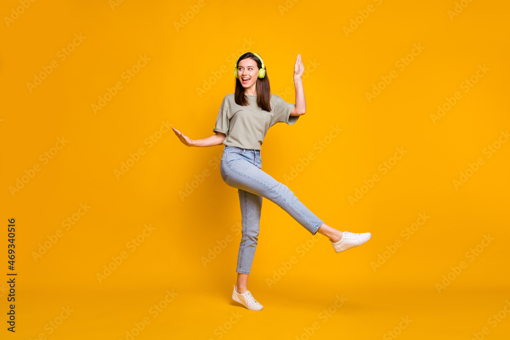 Full length photo of young funny funky woman wear headphones dance raise hands isolated on yellow color background