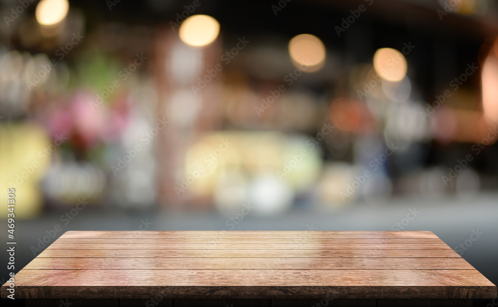 Empty wooden table top with lights bokeh on blur restaurant background.