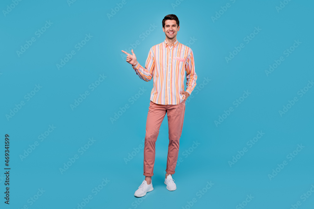 Full size photo of young guy happy positive smile point finger empty space ad advice choice isolated over blue color background