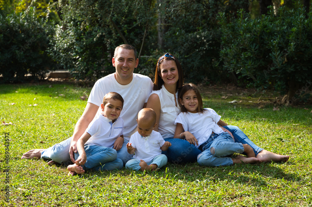 Portrait of happy parents with their three children lying in the park. The eldest daughter is a transgender girl. Concept of family happy united family with children. Portrait of happy parents with their three children lying in the park. The eldest daughter is a transgender girl. Concept of family happy united family with children.
