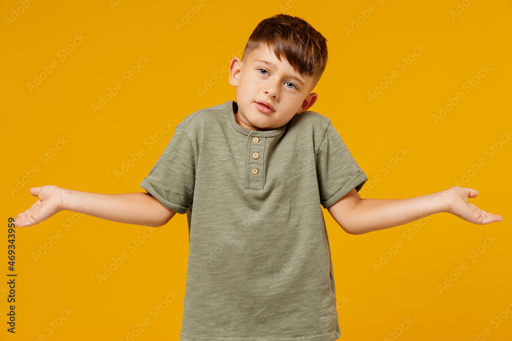 Little small uncertain doubtful caucasian boy 6-7 years old wearing green casual t-shirt spreading hands isolated on plain yellow background studio portrait Mother's Day love family lifestyle concept Little small uncertain doubtful caucasian boy 6-7 years old wearing green casual t-shirt spreading hands isolated on plain yellow background studio portrait Mother's Day love family lifestyle concept