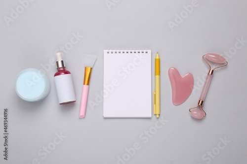 Cosmetology products and accessories with a notepad on a gray background. Therapy plan. Flat lay
