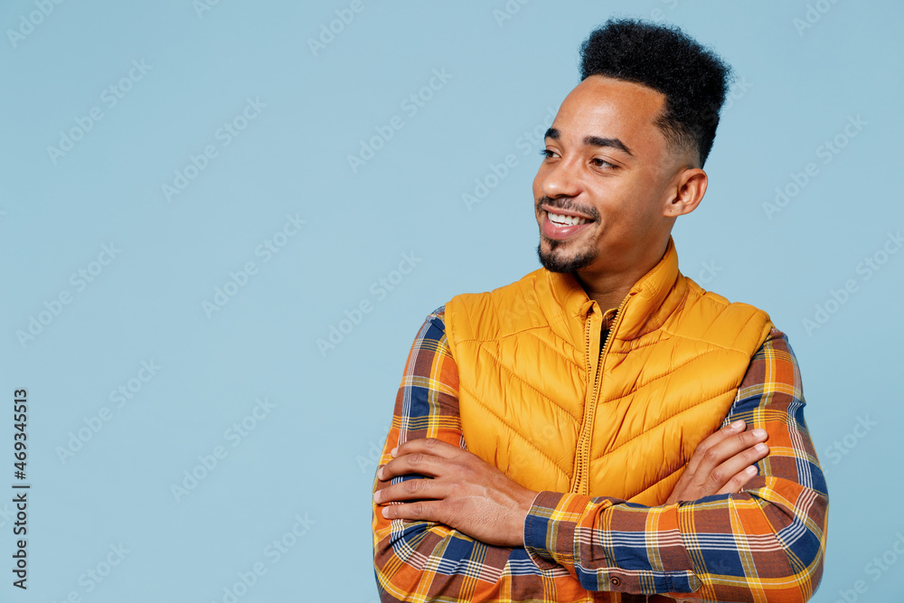 Confident fascinating charming jubilant vivid young black man 20s years old wear yellow waistcoat shirt looking aside hold hands crossed isolated on plain pastel light blue background studio portrait Confident fascinating charming jubilant vivid young black man 20s years old wear yellow waistcoat shirt looking aside hold hands crossed isolated on plain pastel light blue background studio portrait