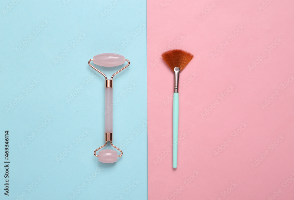 Massage roller and makeup brush on blue pink pastel background