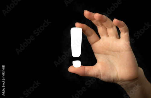 Exclamation sign in hand on a black background. Concept photo of warning, attention