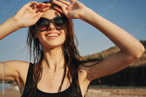 cheerful woman in sunglasses in a swimsuit on the beach sun island © VICHIZH