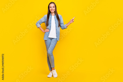 Full length photo of funny young lady index ad wear jeans shirt shoes isolated over yellow color background
