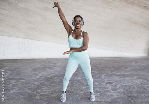 Fit african woman dancing outdoor while wearing wireless headphone