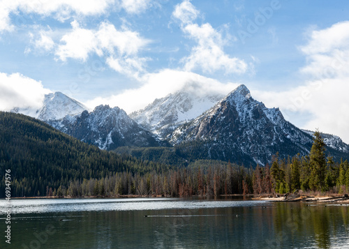 Sawtooth Moutain peaks veiled in clouds, lake with reflection