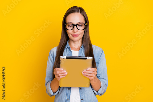 Photo of think mature boss lady hold tablet wear eyewear jeans shirt isolated over yellow color background