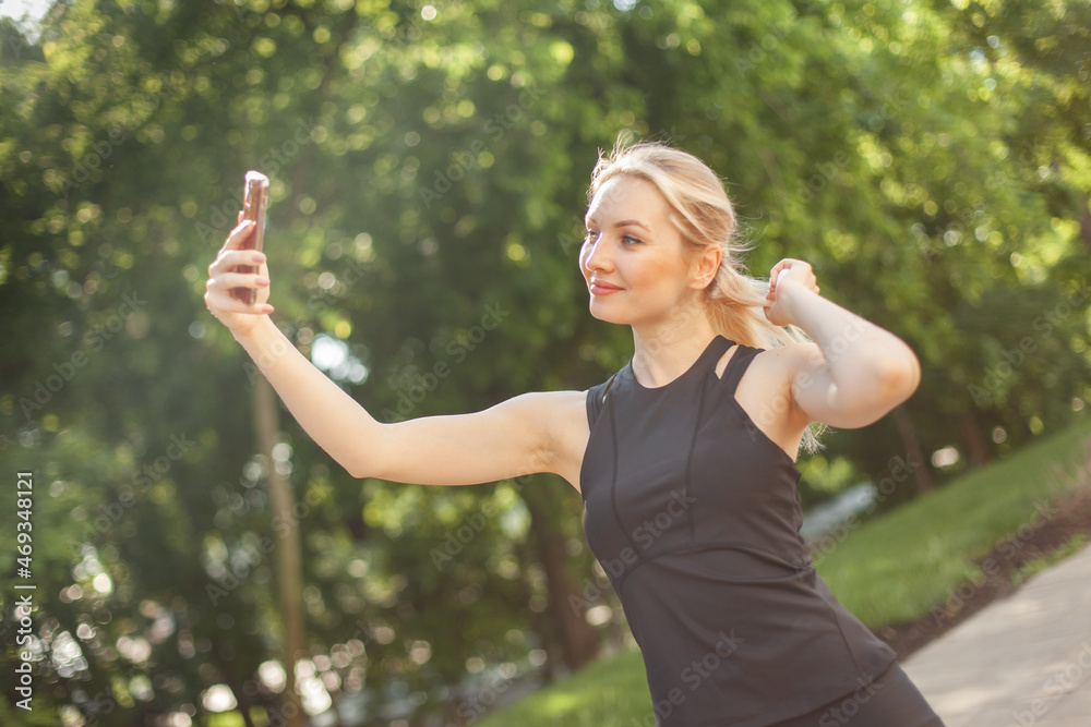 Young fit woman taking a selfie on the phone in the park