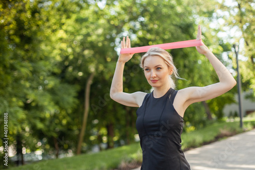 Fit woman exercising with fitness rubber band in the park