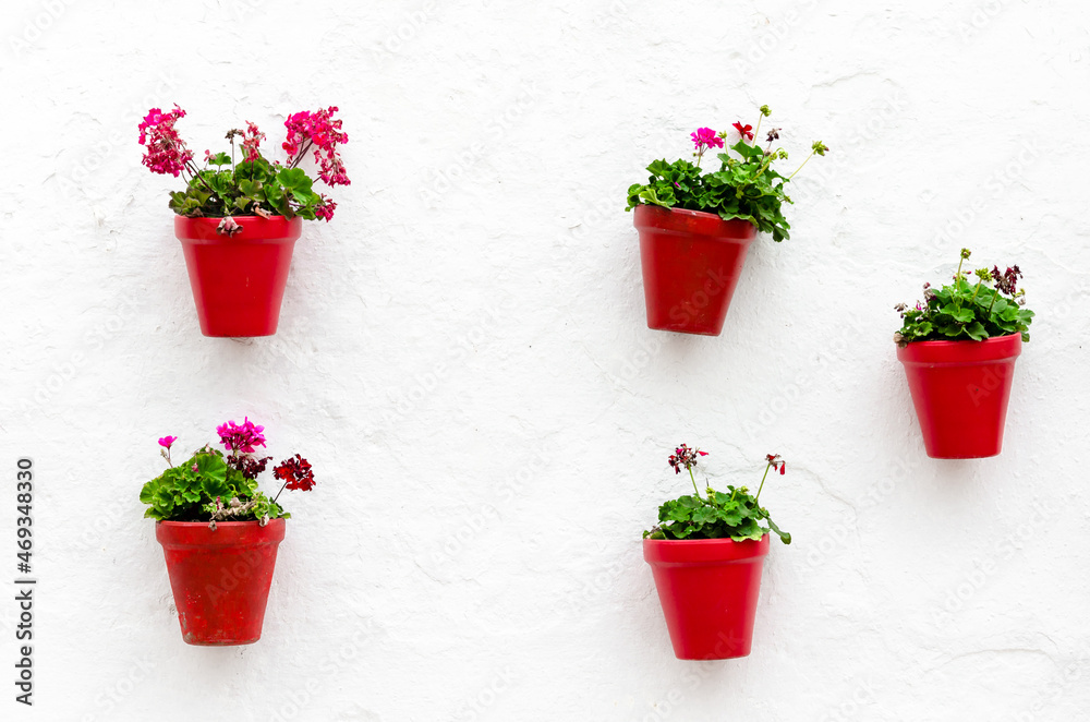 Typical Andalusian white facade, with hanging red pots. Andalusian village, Marbella Typical Andalusian white facade, with hanging red pots. Andalusian village, Marbella