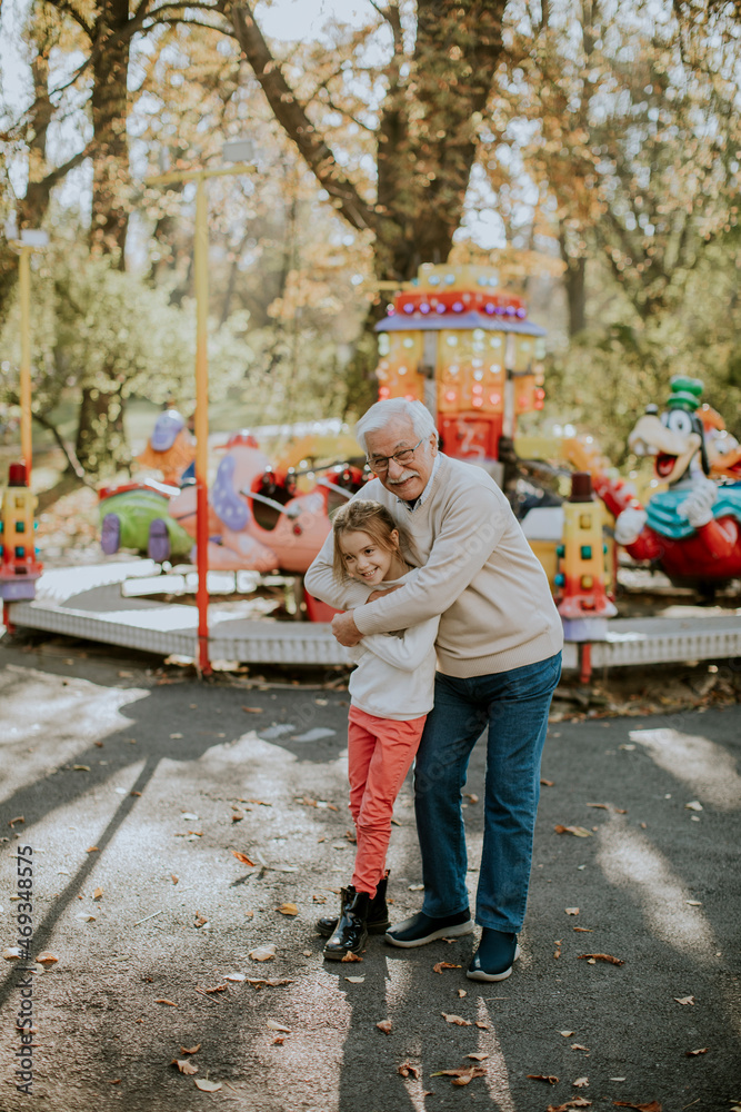 Obraz premium Grandfather having fun with his little granddaughter in the amusement park